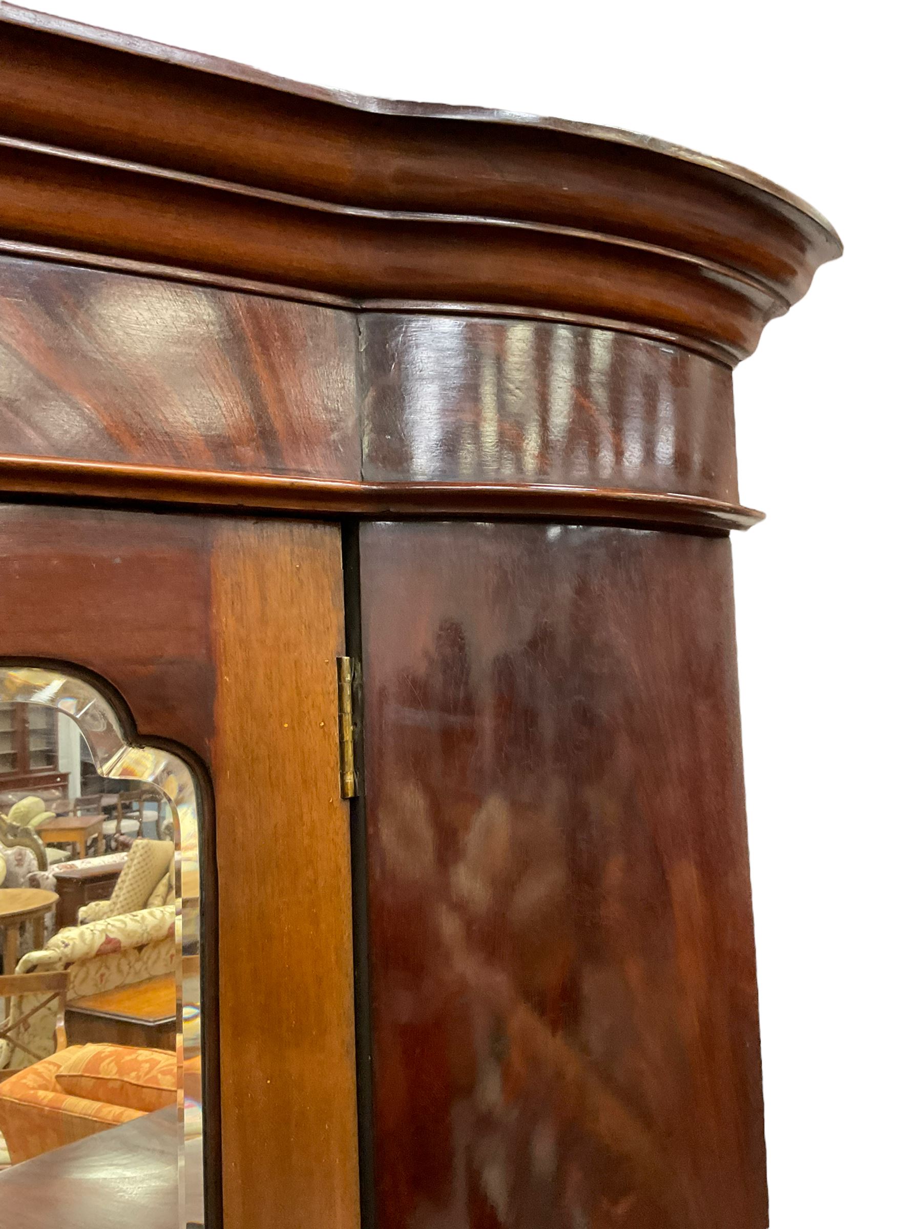 Late 19th century mahogany double wardrobe, projecting cornice over figured frieze, curved uprights enclosing two doors with bevelled mirrors, drawer to base, on splayed bracket feet