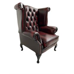 Queen Anne design wingback armchair, scrolled back and arms, upholstered in buttoned oxblood leather with studwork border, raised on cabriole supports