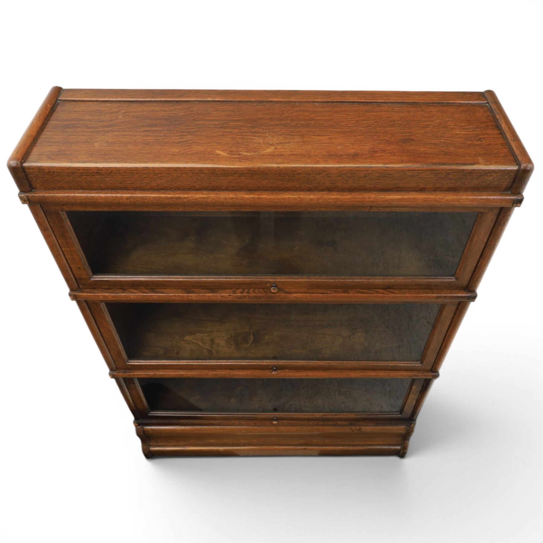Globe Wernicke - early 20th century oak stacking bookcase, three tiers, lift up glazed doors raised on a plinth base