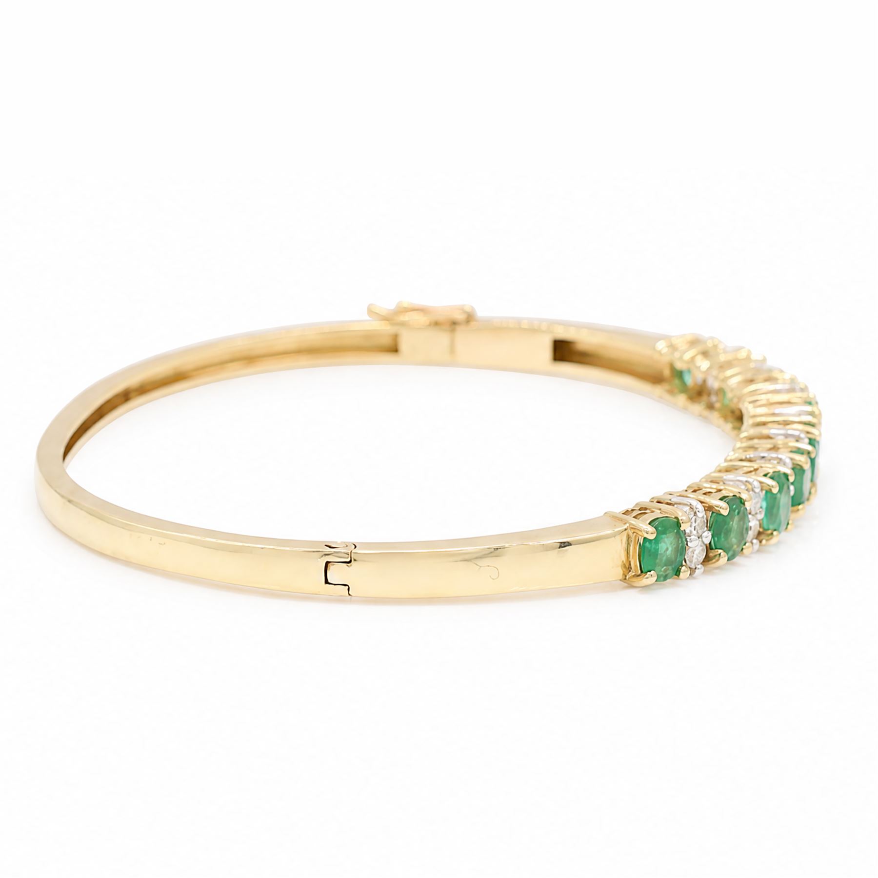 14ct gold emerald and diamond hinged bangle, nine oval cut emeralds, each spaced by two round brilliant cut diamonds, stamped 585, total emerald weight approx  2.15 carat, total diamond weight approx 0.50 carat