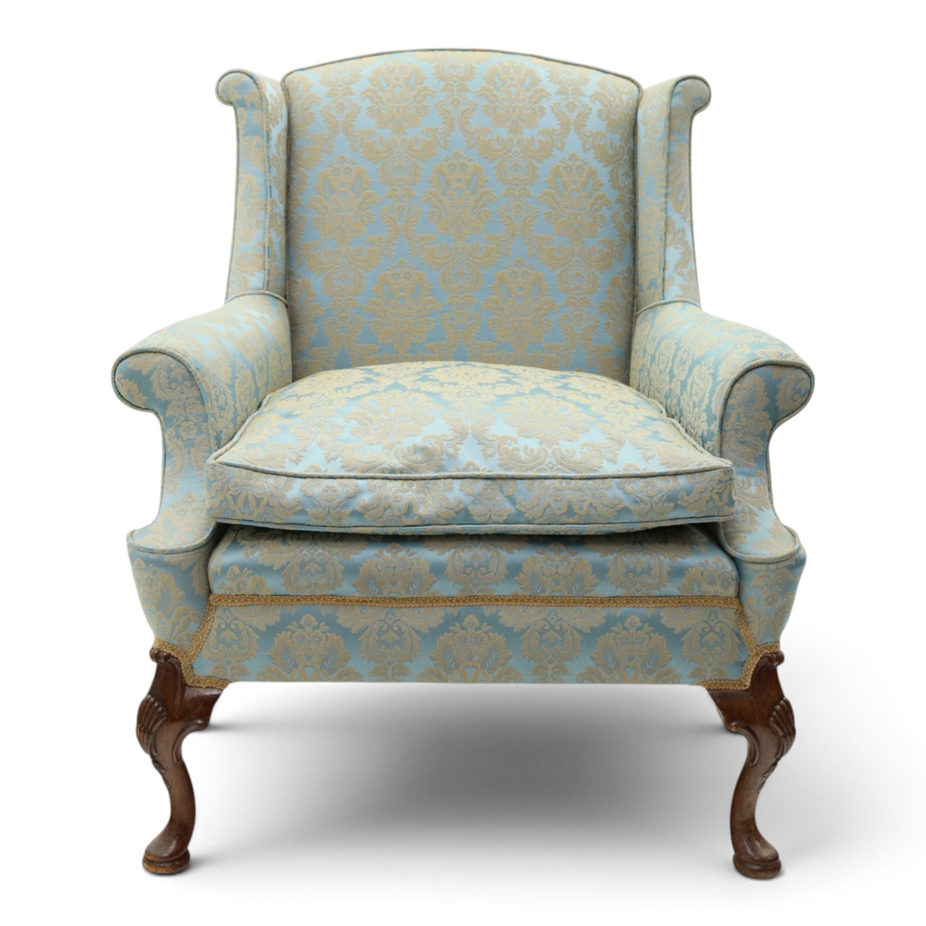 Georgian design carved mahogany framed wingback armchair, high wingback over sprung seat and loose cushion with rolled arms, upholstered in cyan ground gilt foliate damask fabric, on shell-carved cabriole supports with pad feet