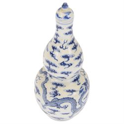 Chinese Kangxi style double-gourd form vase, the blue and white vase surmounted by a domed cover, decorated with dragons chasing a flaming pearl, four-character mark to beneath, H31cm