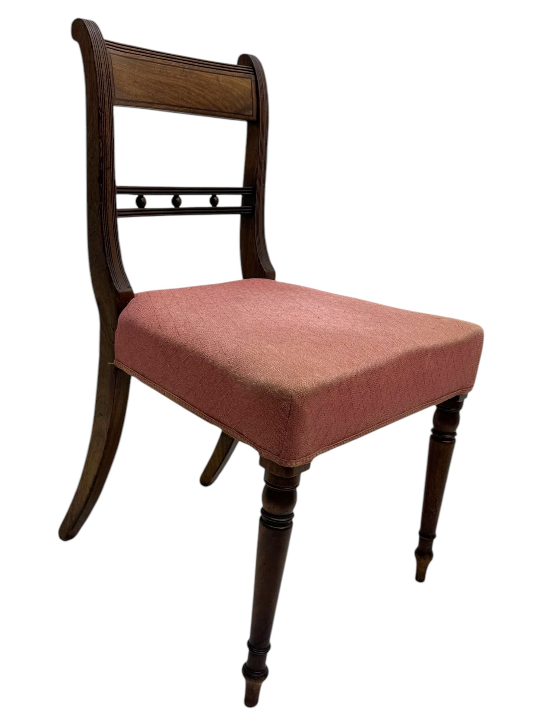 
Late Victorian mahogany extending dining table and four chairs, rectangular top with rounded corners and moulded edge, fitted with two additional leaves, raised on turned and reeded legs with brass castors, with a pair of Victorian mahogany hall chair, with curved top rail and plain splat, padded seat in textured salmon pink fabric, raised on turned and tapering front legs and another pair of early 20th century mahogany dining chair, with shield back and carved pierced splat, serpentine seat rail with striped upholstered cushion, raised on moulded square front legs