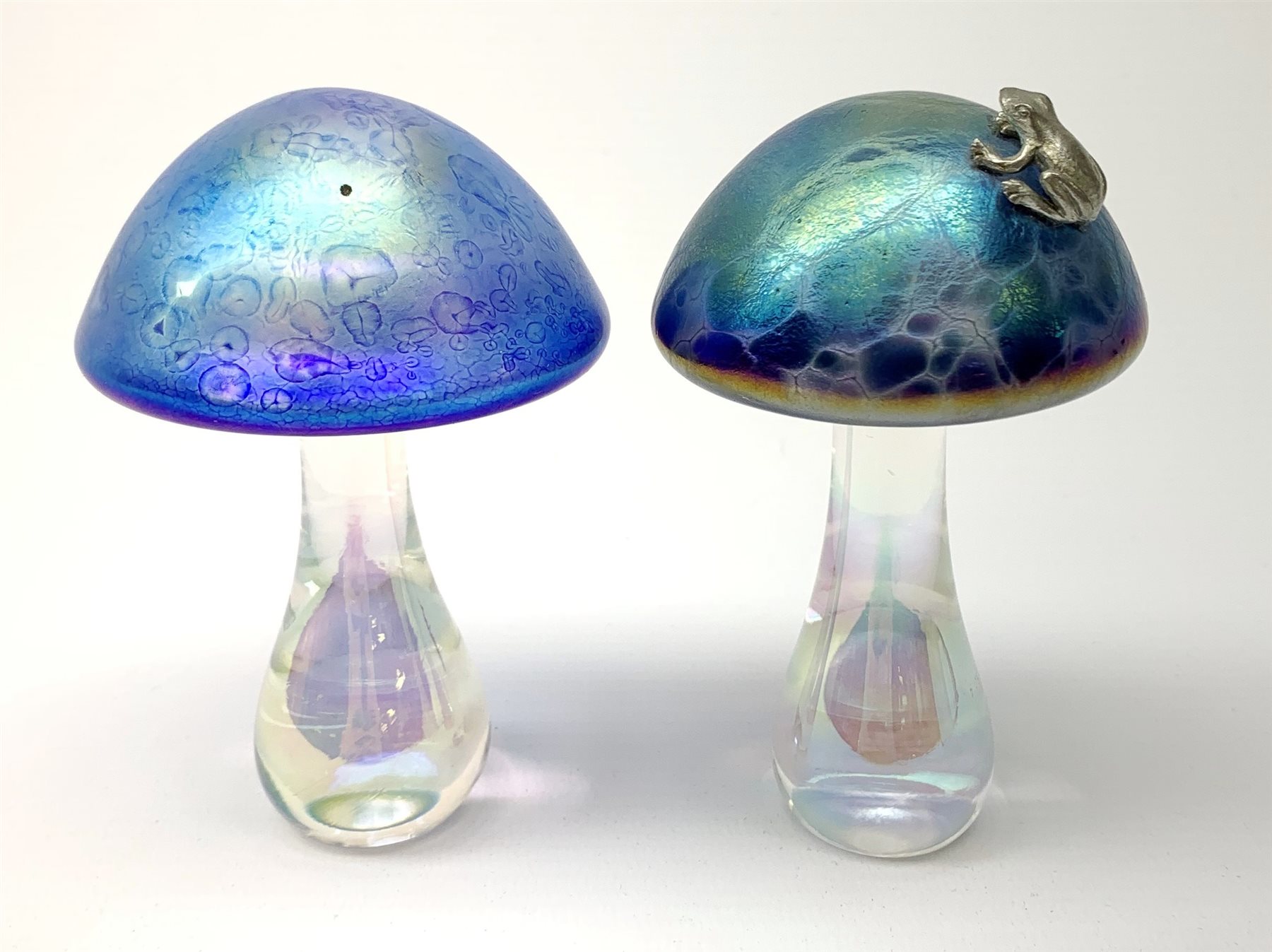 A John Ditchfield Glasform mushroom, in irridescent blue surmounted with a frog, H10.5cm, together with another similar John Ditchfield example. 
