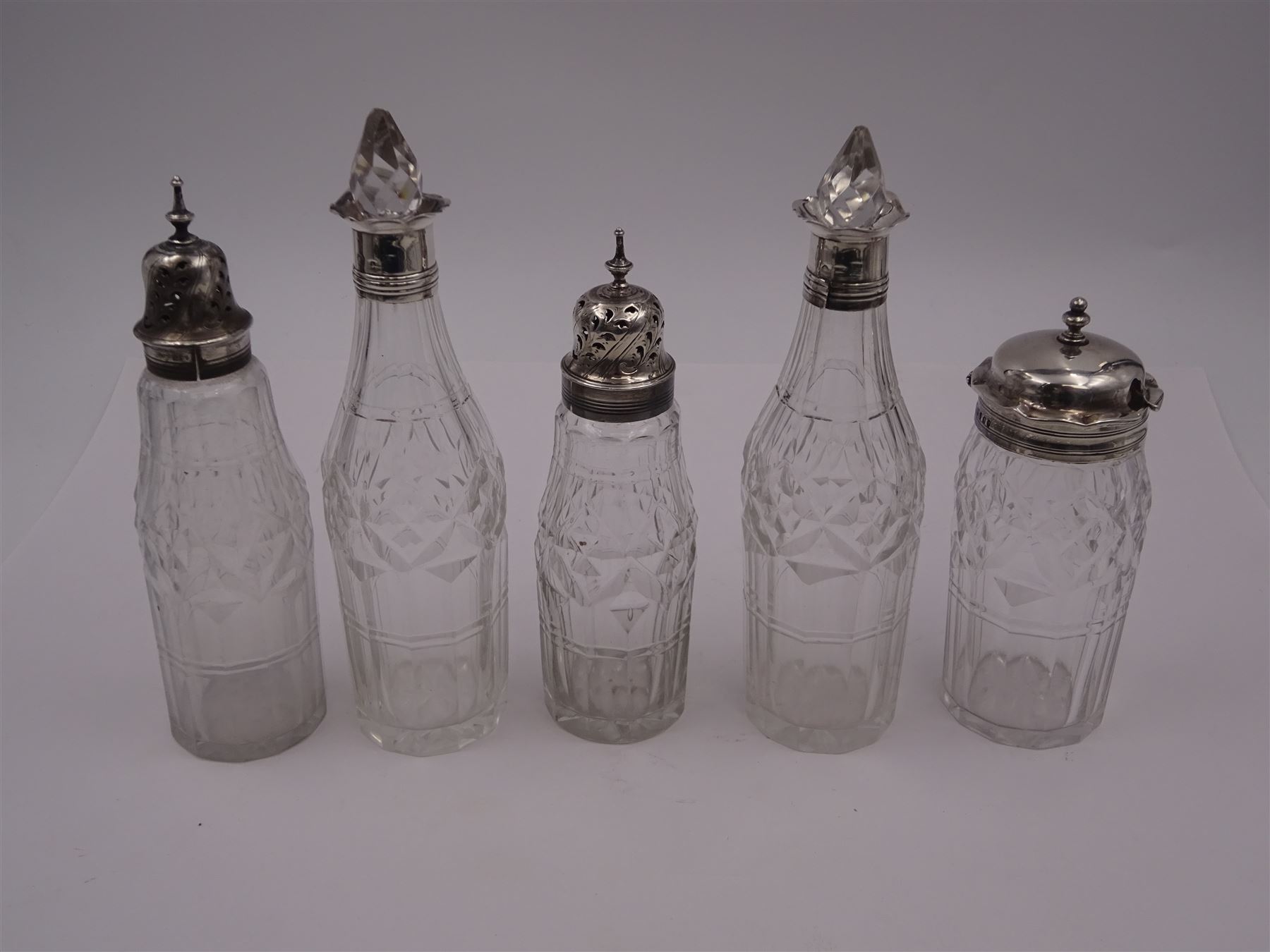 Late 18th century silver cruet stand, of oval form, with pierced sides upon four bun feet, hallmarked to handle Hester Bateman, all other hallmarks indistinct, together with five matched silver mounted cut glass cruet bottles, including some later Victorian examples, hallmarks predominantly indistinct, stand H20cm