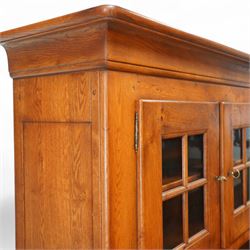 Traditional design solid oak dresser, moulded cornice over twin glazed doors enclosing shelved interior, open centre section, lower base with fielded panel doors opening to shelved cupboards, on plinth base