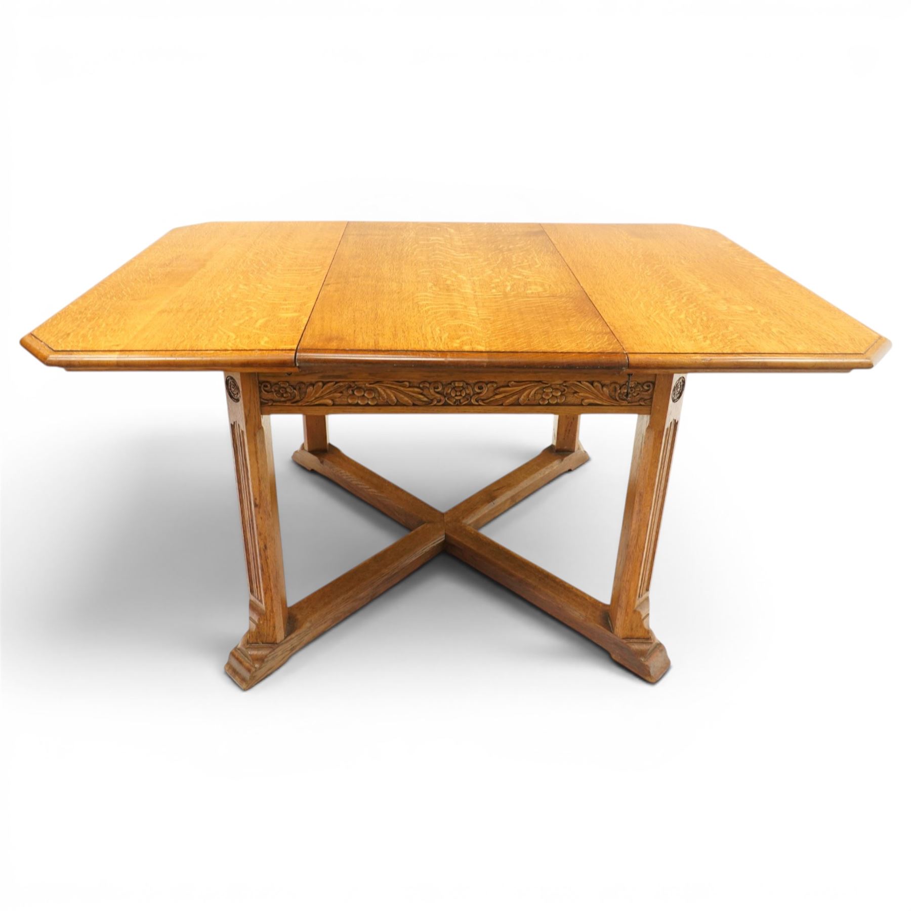 Waring & Gillow - Arts and Crafts oak draw-leaf extending dining table rectangular moulded top with chamfered corners, two additional leaves, carved frieze over fluted section supports, united by low X-shape stretchers