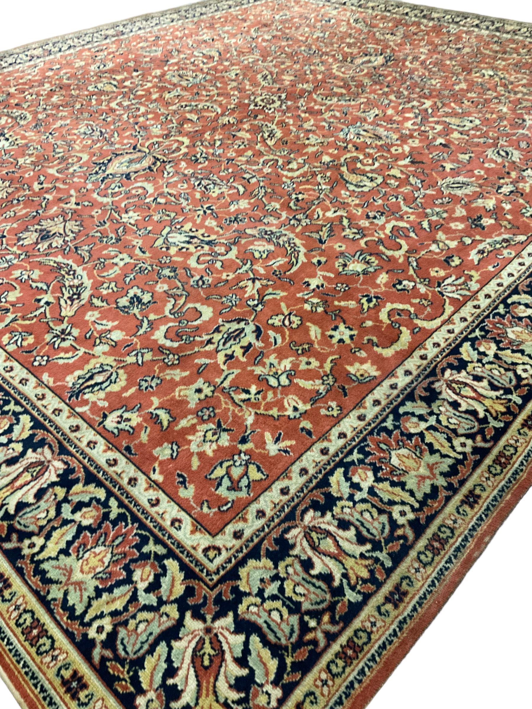 Large Persian design red ground rug, the field decorated with interlacing branches and stylised plant motifs, repeating border with further plant and floral motifs