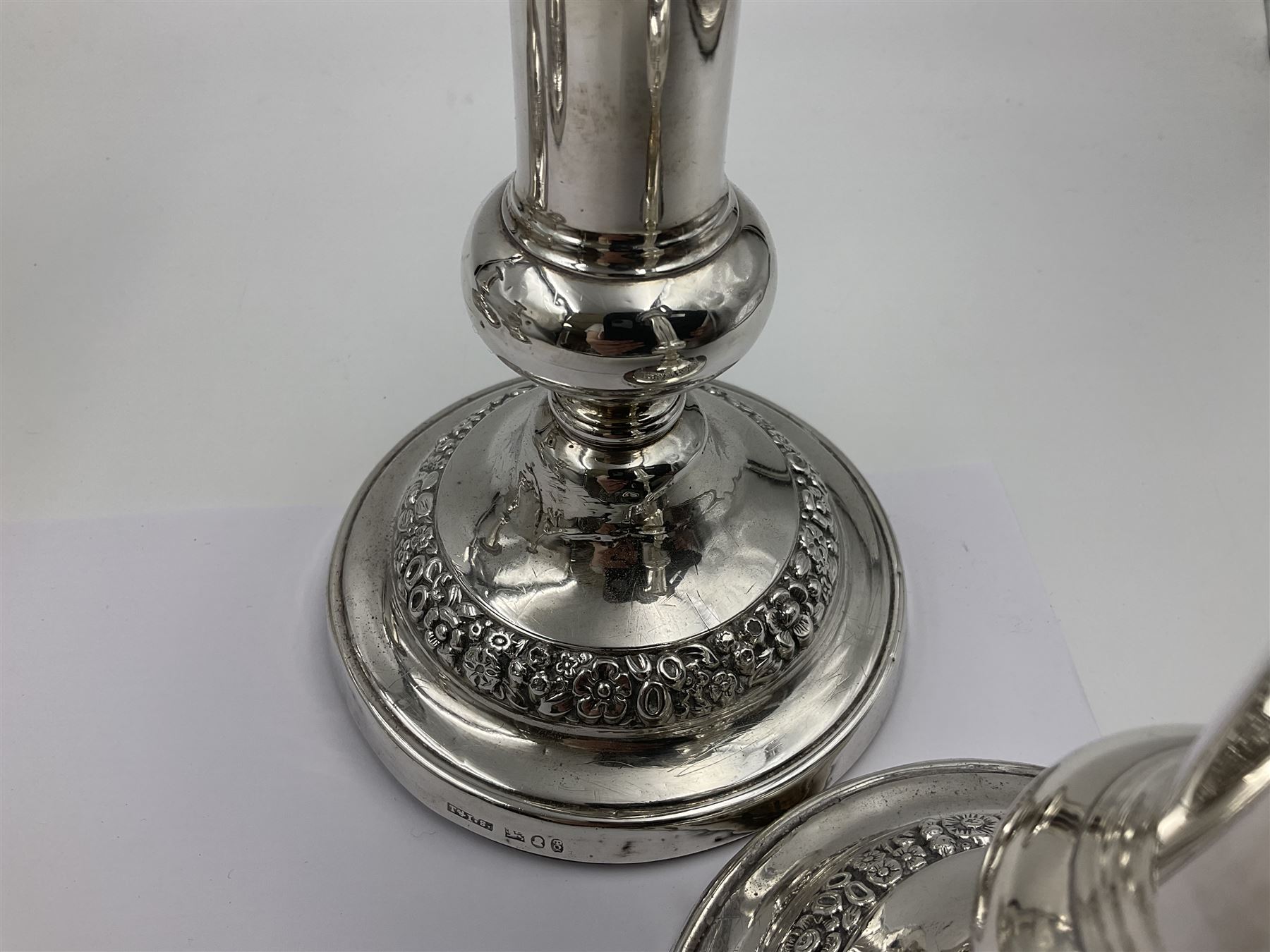 Four George III silver candlesticks, each upon knopped stem and weighted circular stepped foot, the foot and removable sconce repousse decorated with a band of flower heads, hallmarked to sconce and foot Thomas & John Settle, Sheffield 1820, H17.5cm