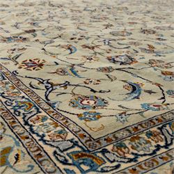 Persian Kashan rug, cream ground decorated with an all-over pattern of interlaced floral stems, rosettes and palmettes in blue, gold and rust tones, framed by layered floral borders, woven in the Kashan region of Iran
