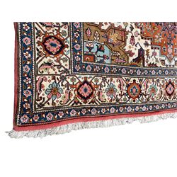 Large Persian carpet, the geometric and stylised floral medallion on rust ground field decorated with stylised plant motifs, guarded ivory border with repeating pattern