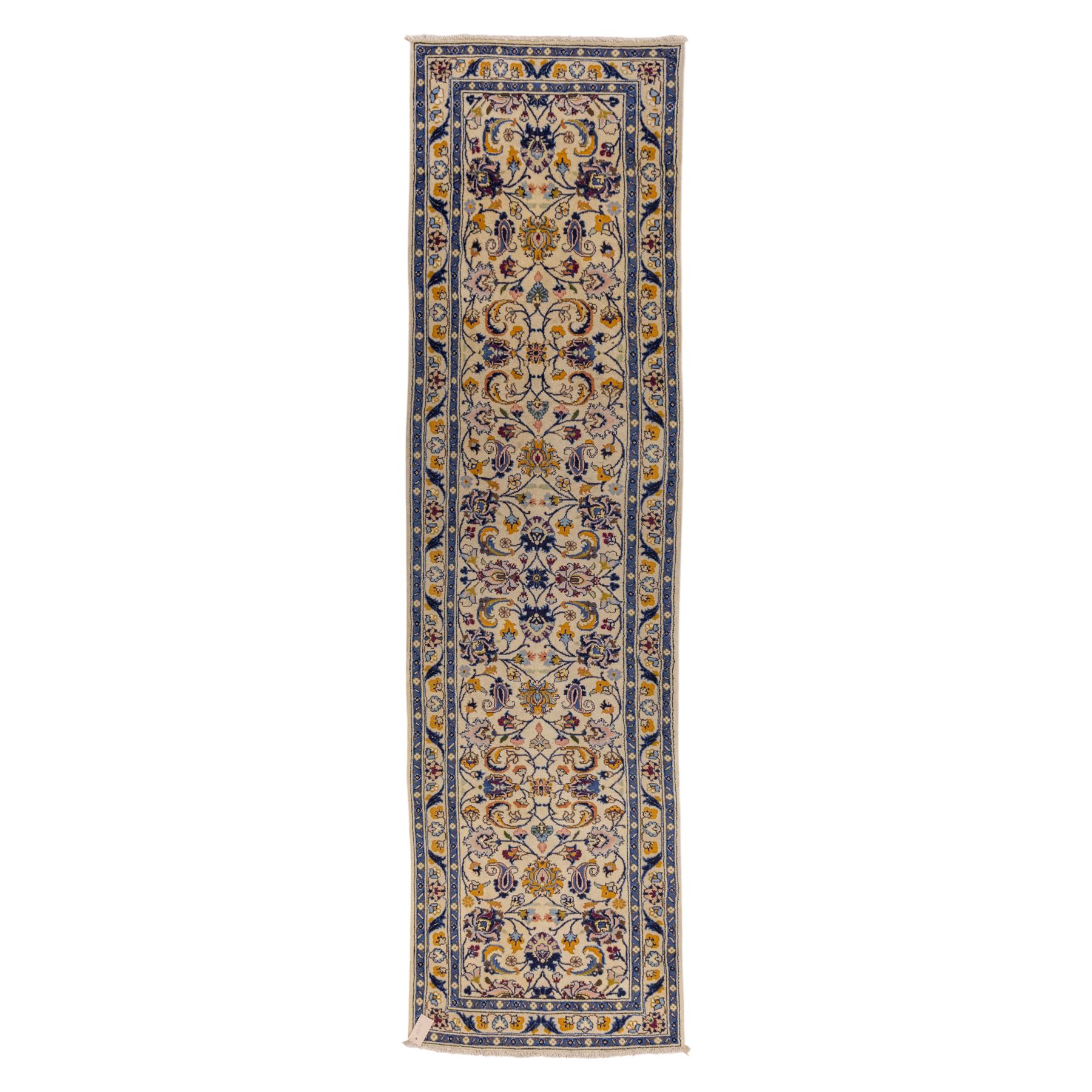 Central Persian Kashan hand-knotted runner, ivory field decorated with an elegant all-over scrolling vine design composed of finely drawn palmettes, floral strays and arabesques in a continuous lattice, principal border on an indigo ground decorated with palmette and vine scroll, flanked by multiple narrow guard stripes, with cotton fringe ends 