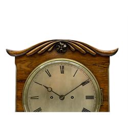 A William IV c1820 twin fusee bracket clock in a rosewood case with a crested top and applied carving to the front, with a chamfered rectangular plinth raised on four bun feet, canted case corners with brass inlay, silk backed brass sound frets to the sides and a fully glazed door to the rear, with an 8” silvered circular dial, engraved Roman numerals, minute track and non-matching steel hands, cast brass bezel and flat bevelled glass, eight-day striking movement striking the hours on a bell. With Pendulum and pendulum lock. 