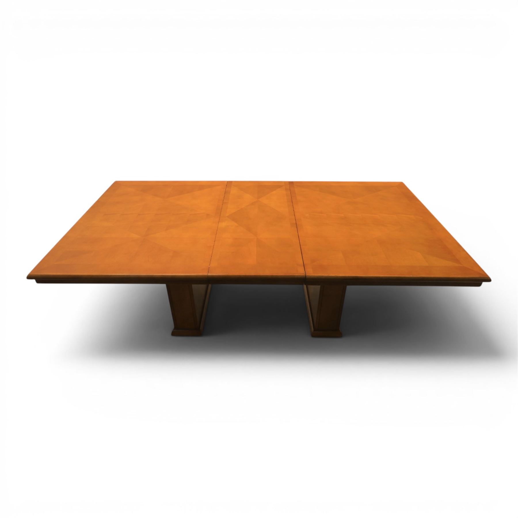 Modern Art Deco design walnut extending dining table, rectangular top with rounded moulded edge, geometric parquetry veneered panels, extending action with additional leaf extending to 220cm, on twin panelled pedestal supports with stepped plinth feet