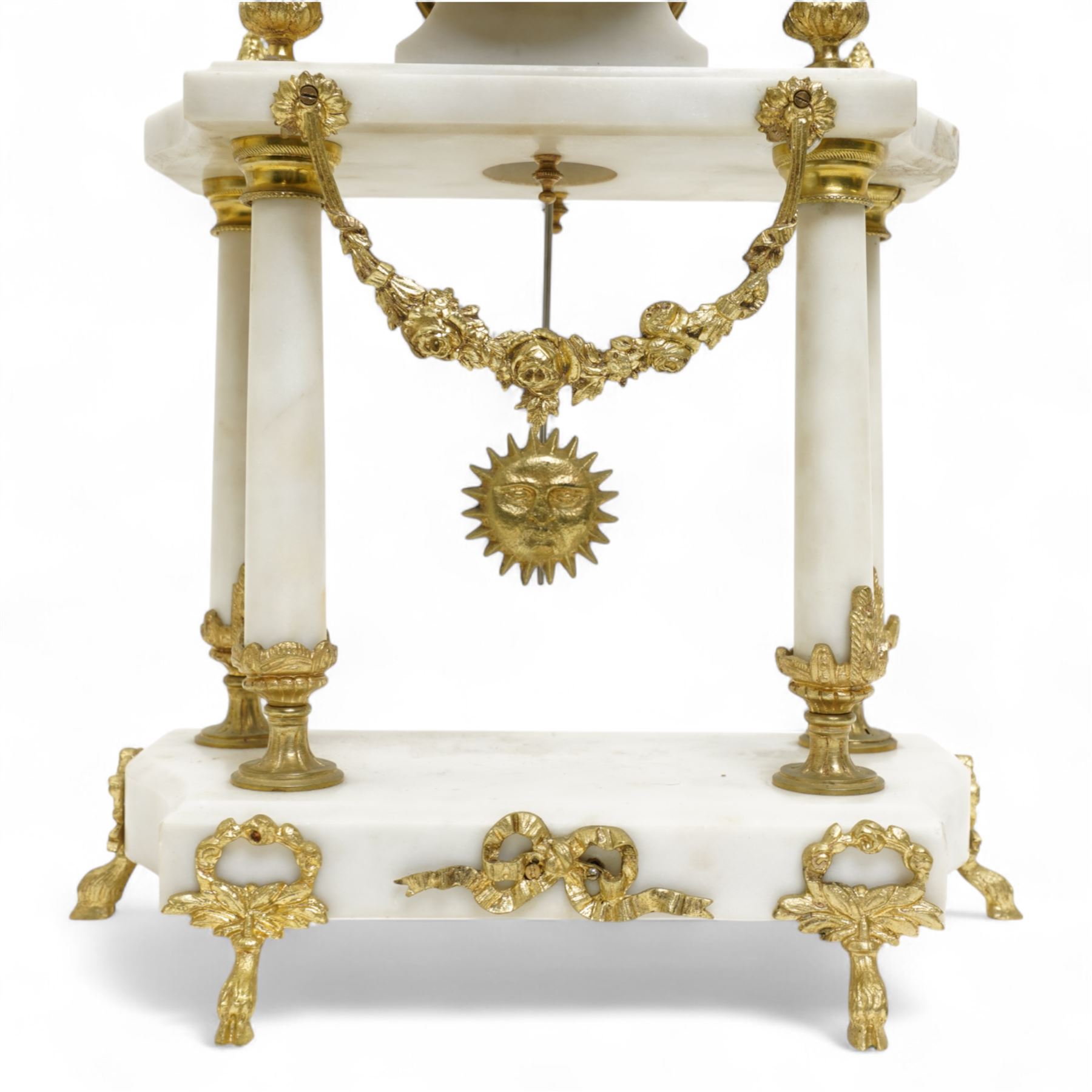 French-Early 20th century 8-day white marble and gilt metal striking portico mantle clock and garniture, Parisian drum movement with a white enamel dial, Arabic numerals and garland swags, two train countwheel striking movement sounding the hours and half hours on a bell. With a matching pair of conforming urns with gilt mounts. 