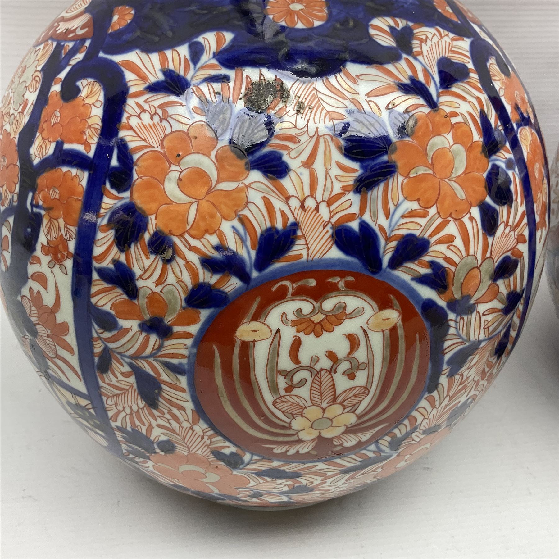 Pair of large 19th century Japanese Imari porcelain bottle vases, painted with shaped reserves of peonies, chrysanthemums and prunus blossom, each H46cm