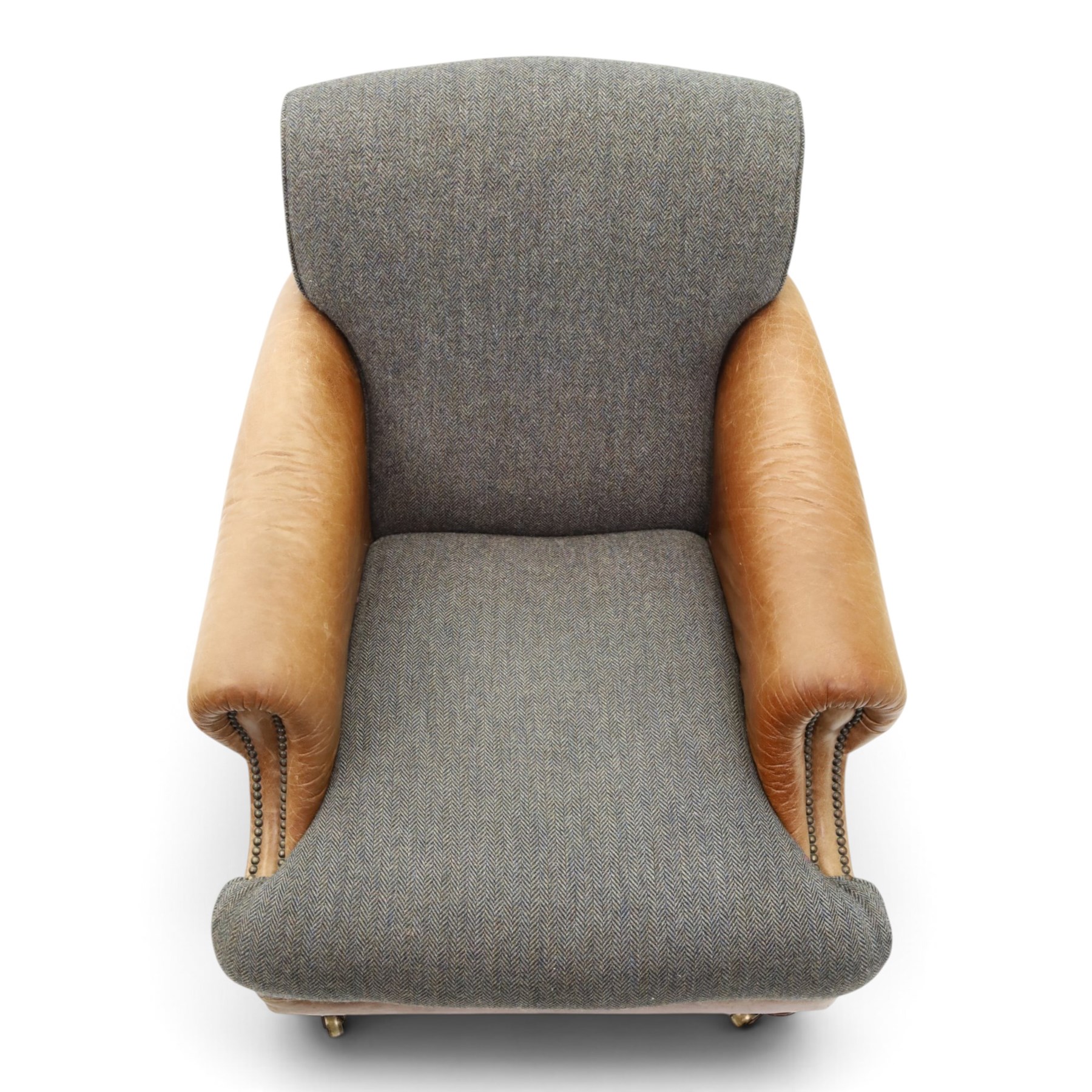 Tetrad - 'Taransay' Harris Tweed and tan leather club armchair, Howard shape with reclined back over deep seat and rolled arms with studwork, raised on turned front supports with castors, the sides and arms upholstered in tan leather with seat and back in herringbone-stitched Harris Tweed