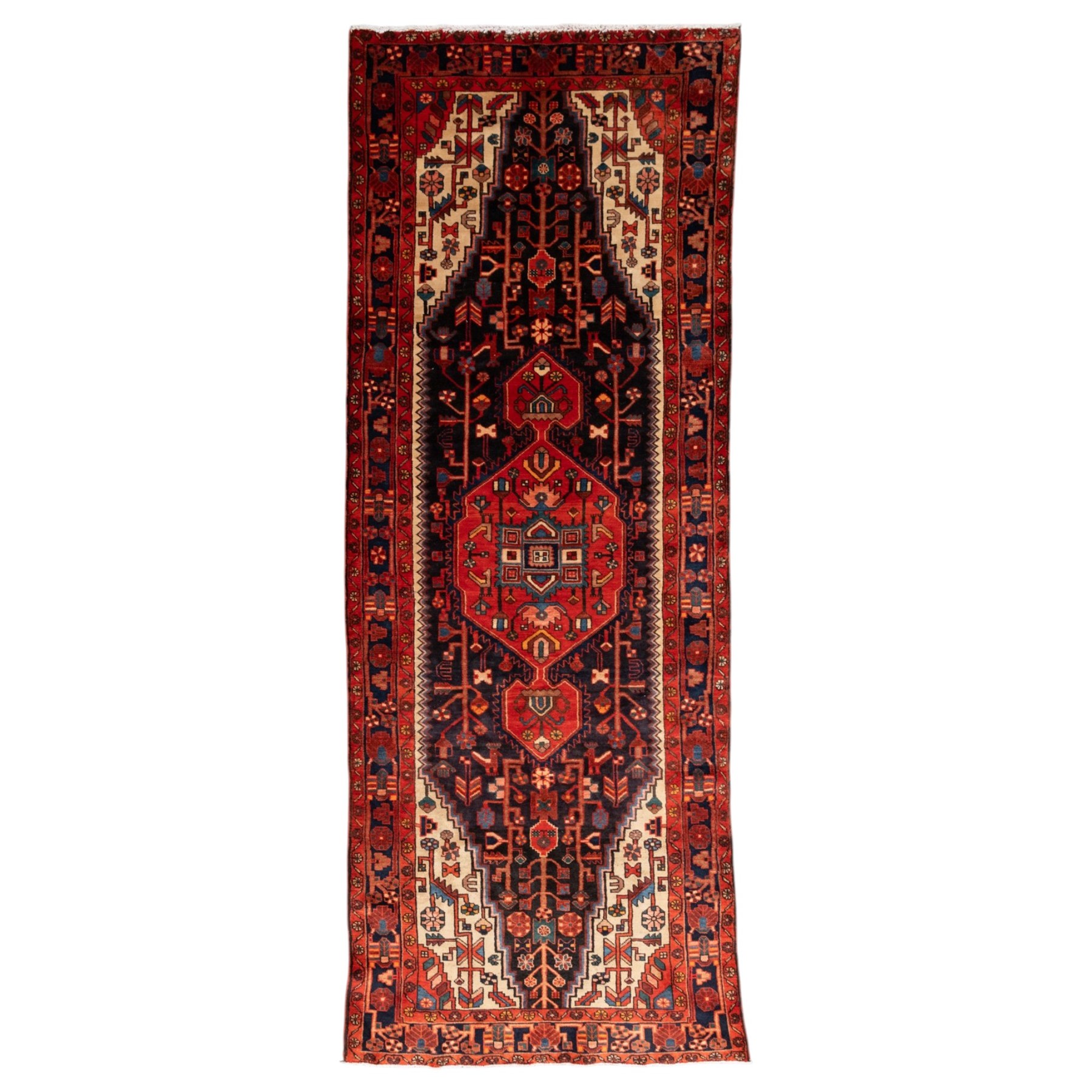 North West Persian runner, the indigo field centred by a red elongated hexagonal medallion with pendant motifs, surrounded by angular flowering stems, ivory stepped floral spandrels, enclosed by an indigo palmette border and red floral guard bands