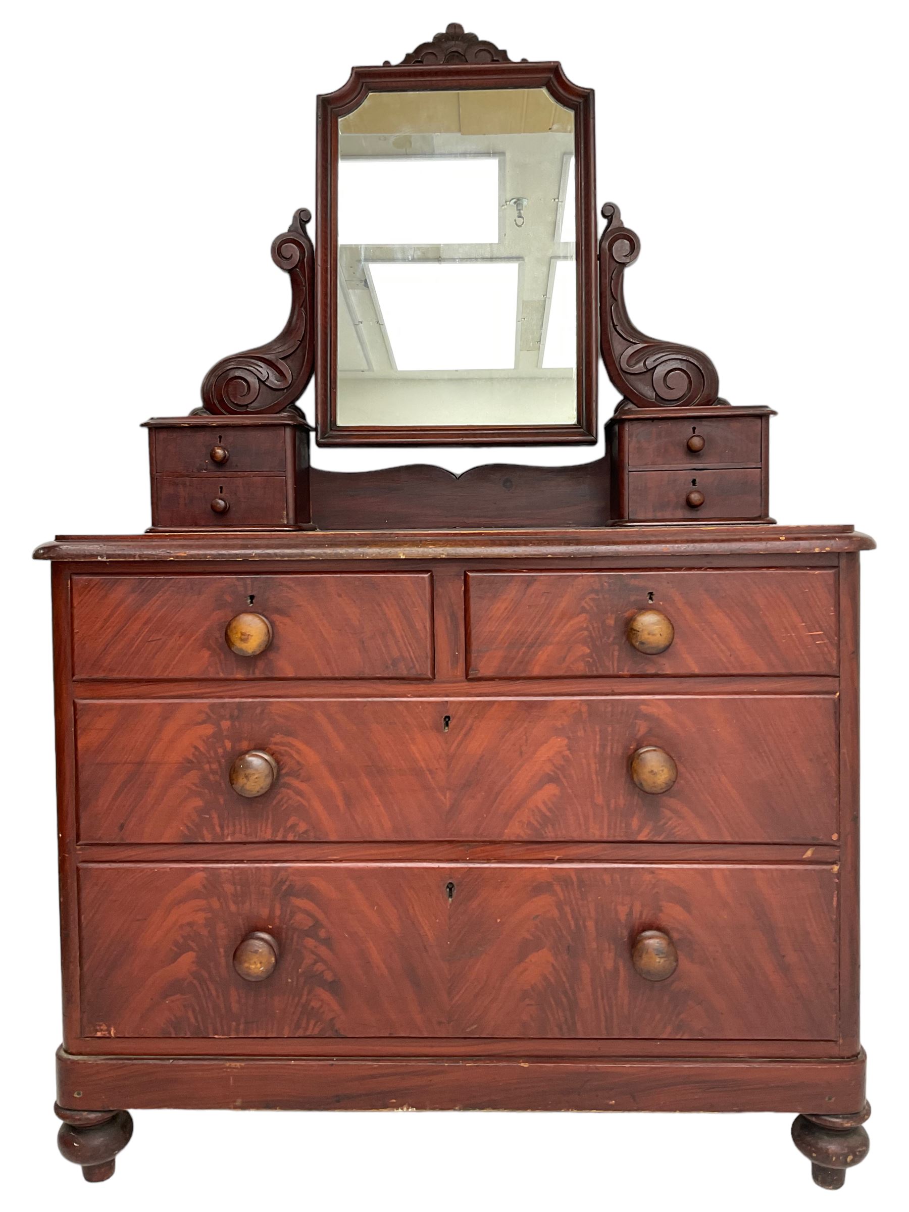 Victorian scumbled pine dressing chest, raised swing mirror in moulded frame with scrolled carved pediment, foliage S-scroll carved supports over trinket drawers, moulded rectangular top with rounded corners over two short and two long drawers, skirted base on turned feet, scumbled to resemble mahogany 