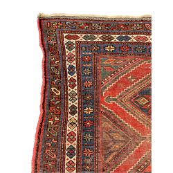 Kurdish crimson ground rug, the field decorated with four lozenge medallions, triple band border decorated with stylised flower heads