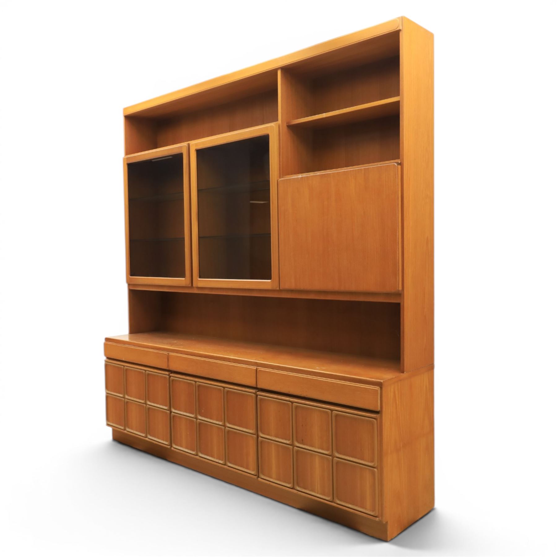Mid-20th century teak wall display unit, featuring two glazed cupboards and fall front compartment with open shelves, above three drawers and cupboards to the base