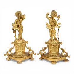 Pair of 19th century ormolu putto figures, each modelled stood with foliate support to backs, upon a naturalistic base upon cylindrical plinth each with twin leafy tendril supports, each plinth with inset Sevres type painted panel of a cherub, upon a shaped base with four compressed disk feet, the front facing with leaf mount, H29cm