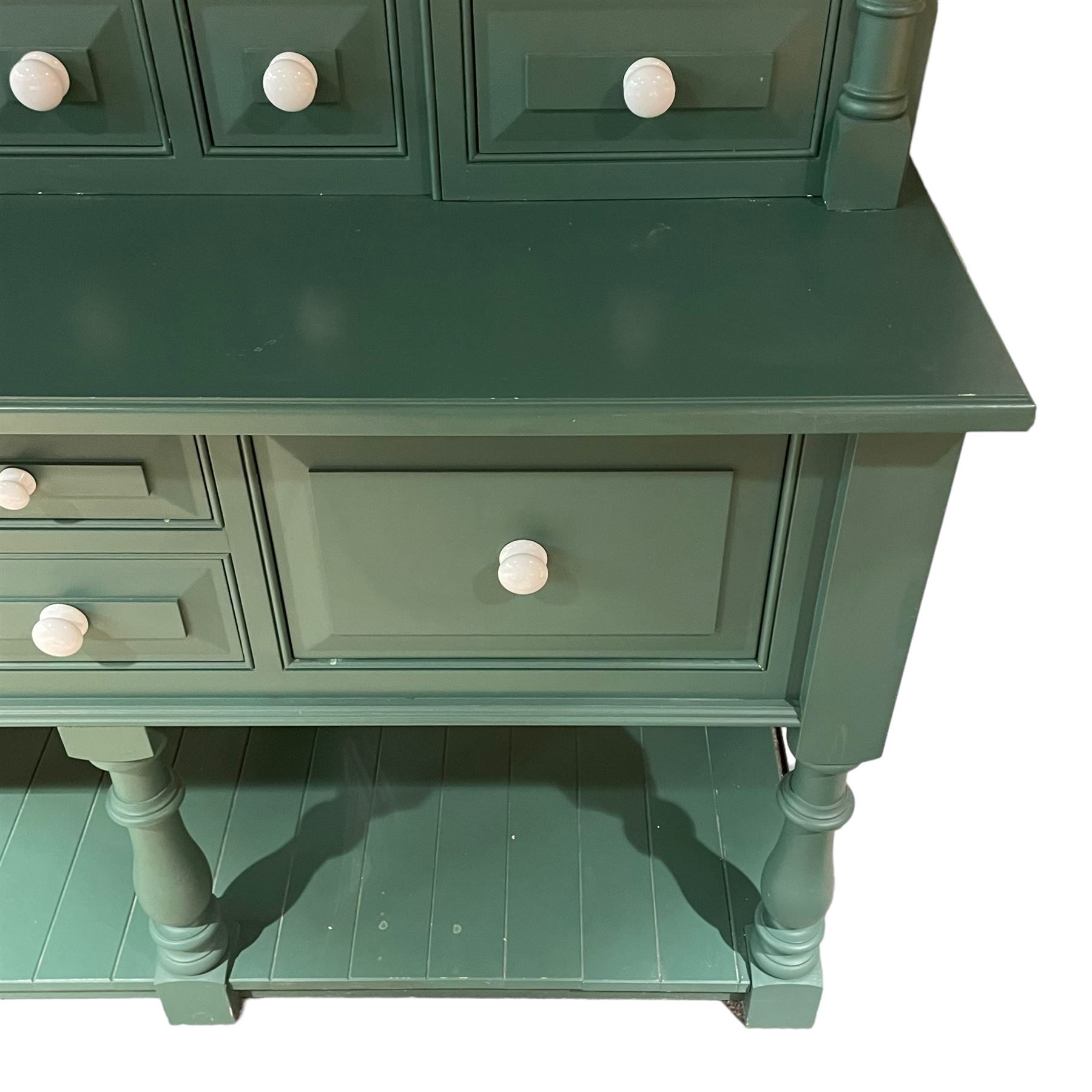 Large contemporary teal green painted kitchen dresser, projecting cornice over three open shelves flanked by cupboard with five spice drawers below, the base fitted with four assorted drawers, raised on turned vasiform supports united by undertier