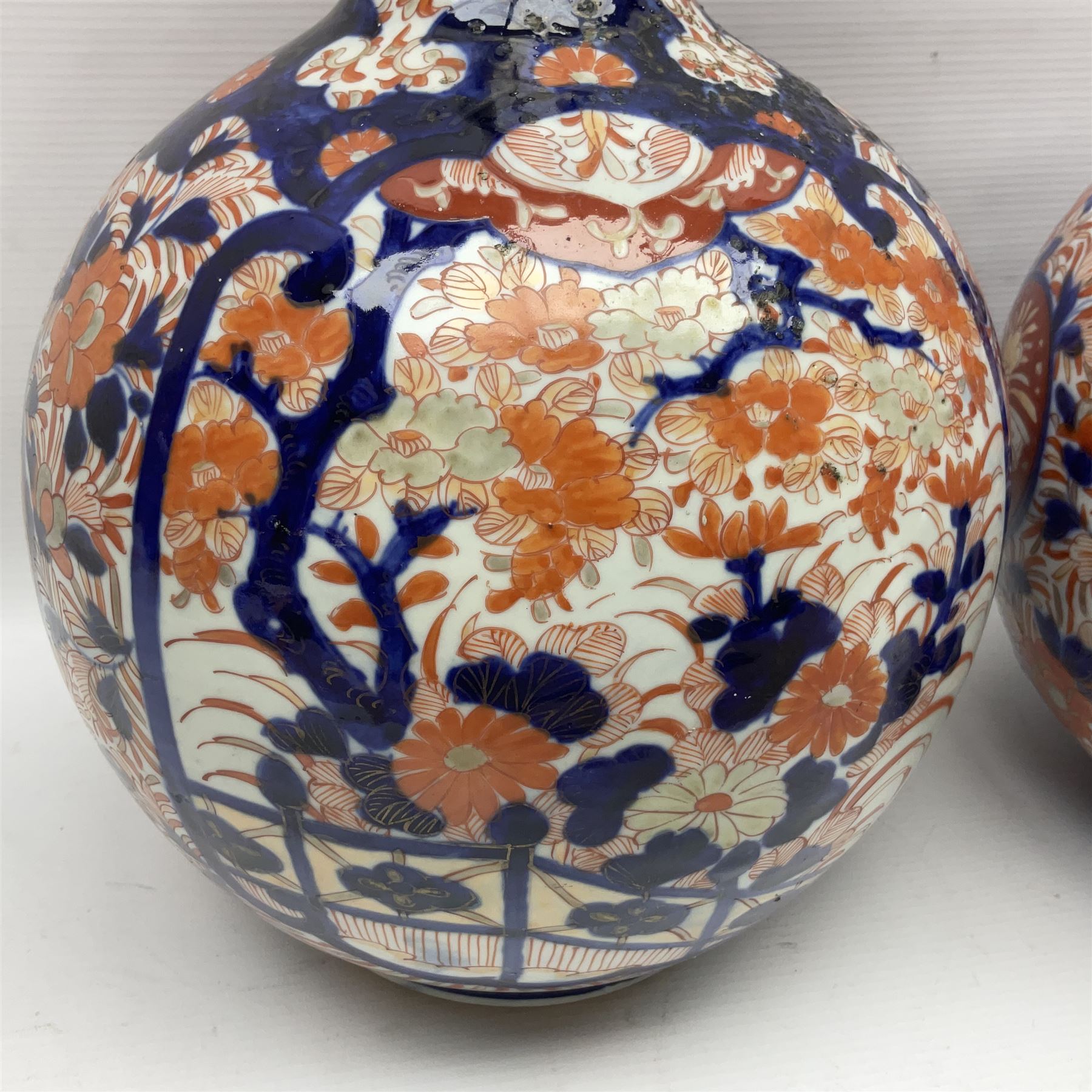 Pair of large 19th century Japanese Imari porcelain bottle vases, painted with shaped reserves of peonies, chrysanthemums and prunus blossom, each H46cm