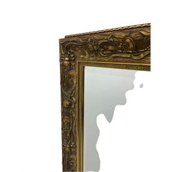 Art Nouveau design gilt framed wall mirror, rectangular bevelled plate, the frame decorated with lotus and lilypad motifs amongst stylised reeds