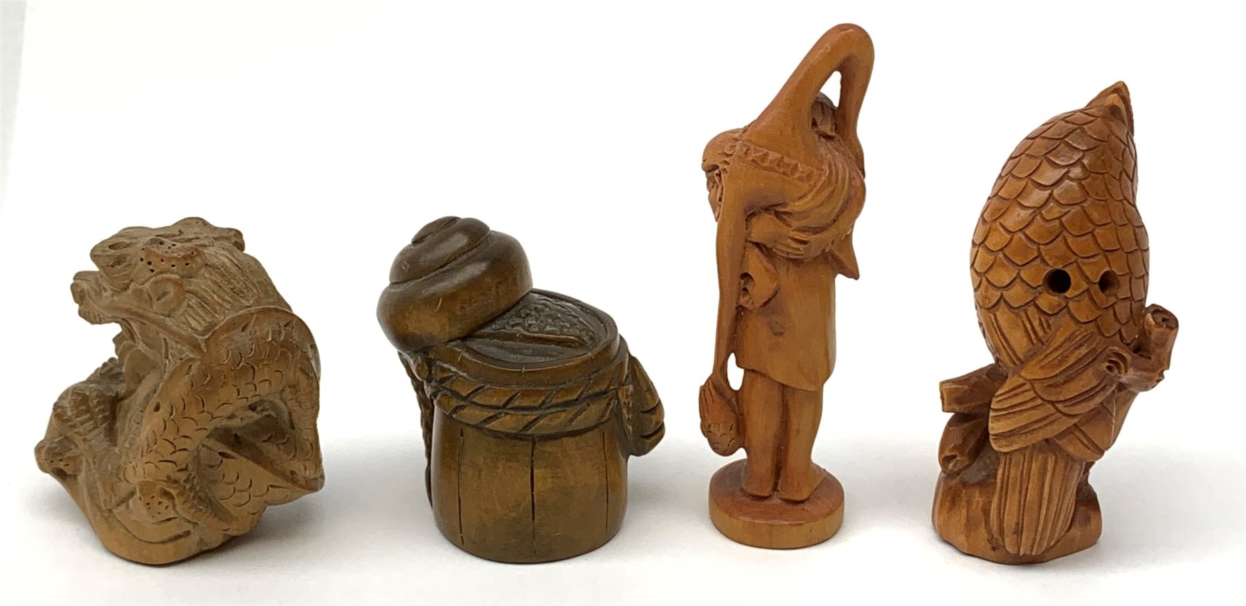 Four carved wooden Japanese netsukes, modelled as a dragon, two snails upon a log, a bird perched upon a branch, and a fisherman with figure upon his back, each signed beneath. (4). 