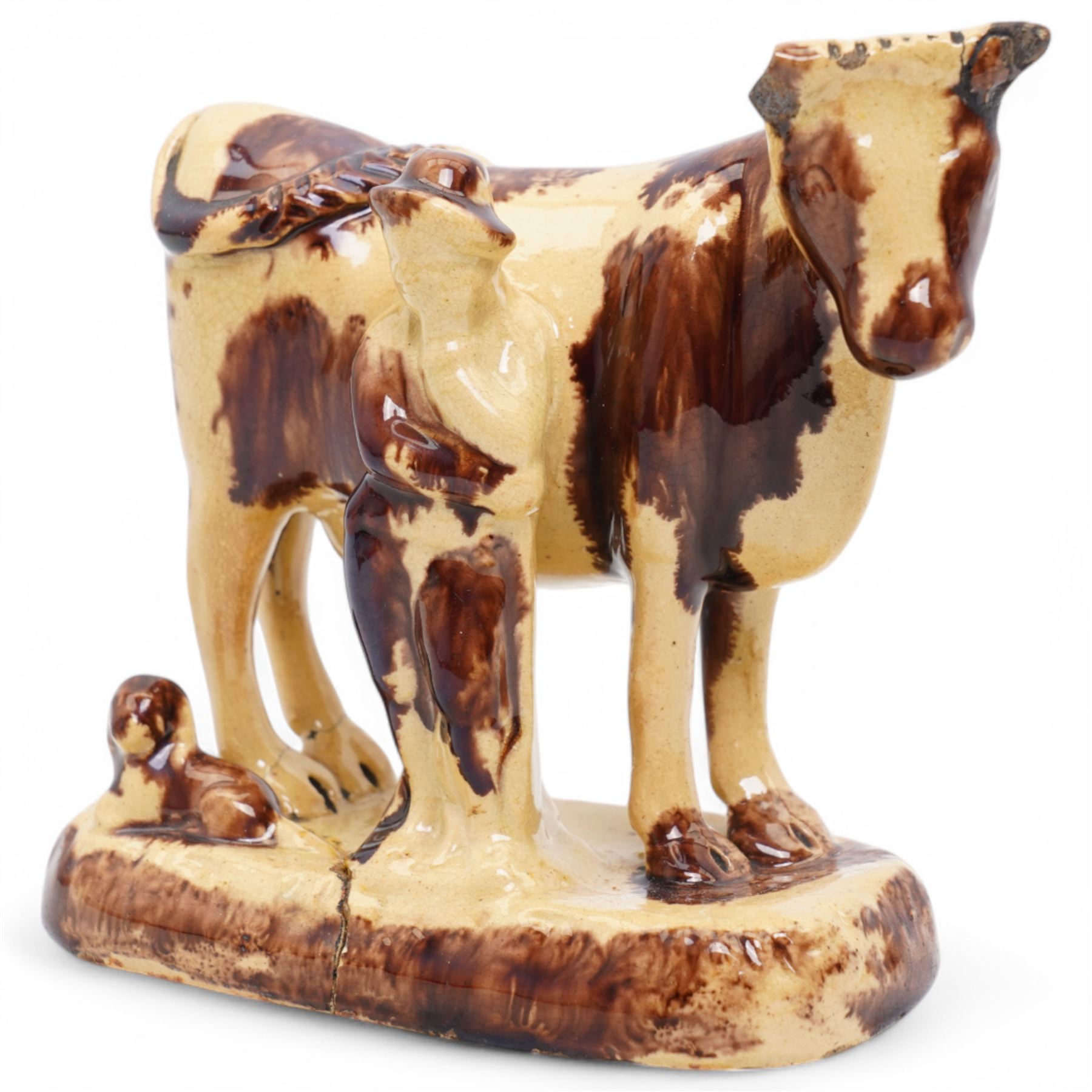 Early 19th century pottery model of a cow with drab colouring accompanied by a standing figure and a dog on naturalistic base, possibly South Yorkshire L14cm x H14cm