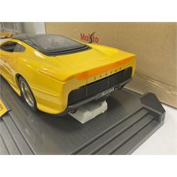 Two Maisto 1:12 scale cars comprising 1992 Jaguar XJ220 Racing car in yellow and 1992 Jaguar XJ220 in metallic green, both on plinths with original boxes