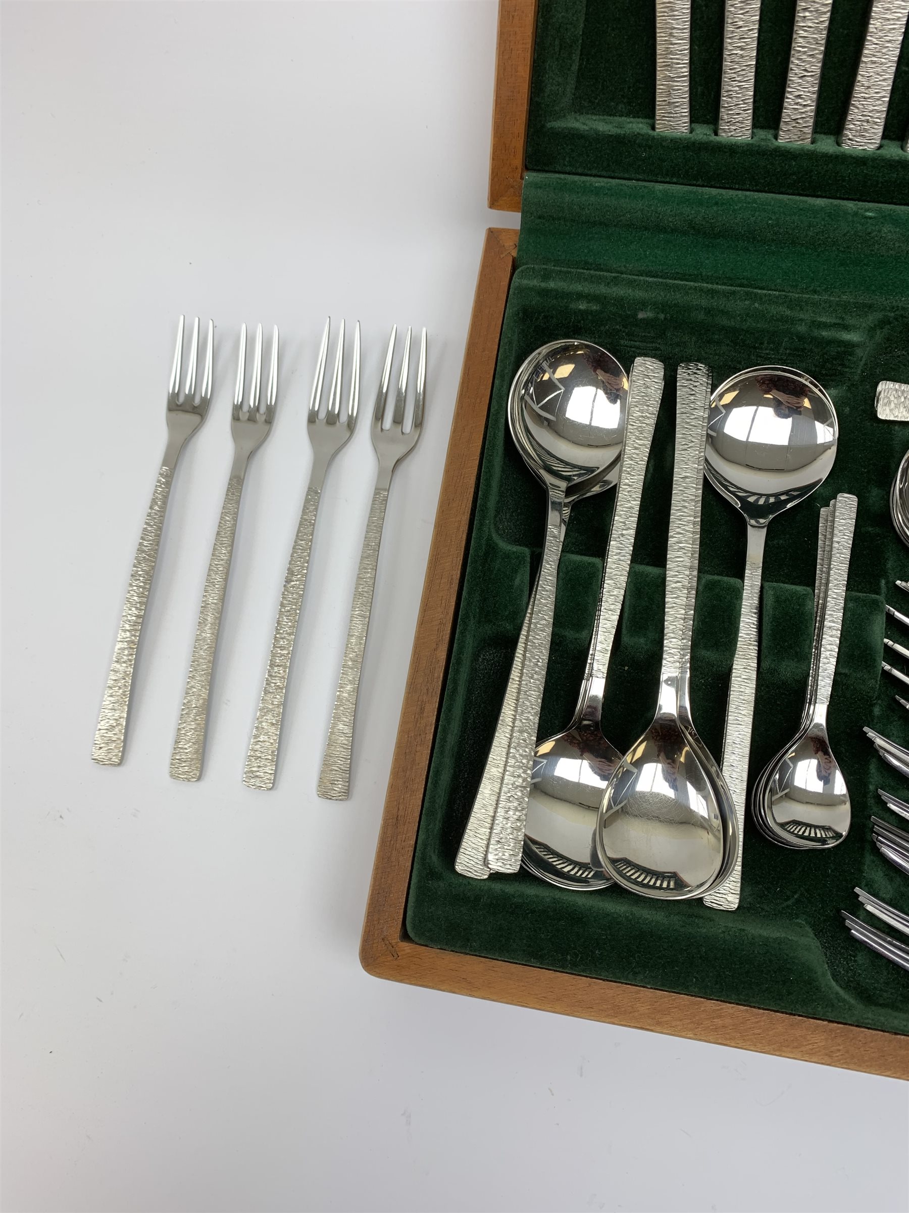 A canteen of bark effect stainless steel cutlery by Gerald Benney for Viners Studio, in a teak case. 