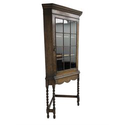 Early to mid-20th century oak corner display cabinet, projecting cornice over astragal glazed door, on spiral turned supports joined by stretchers