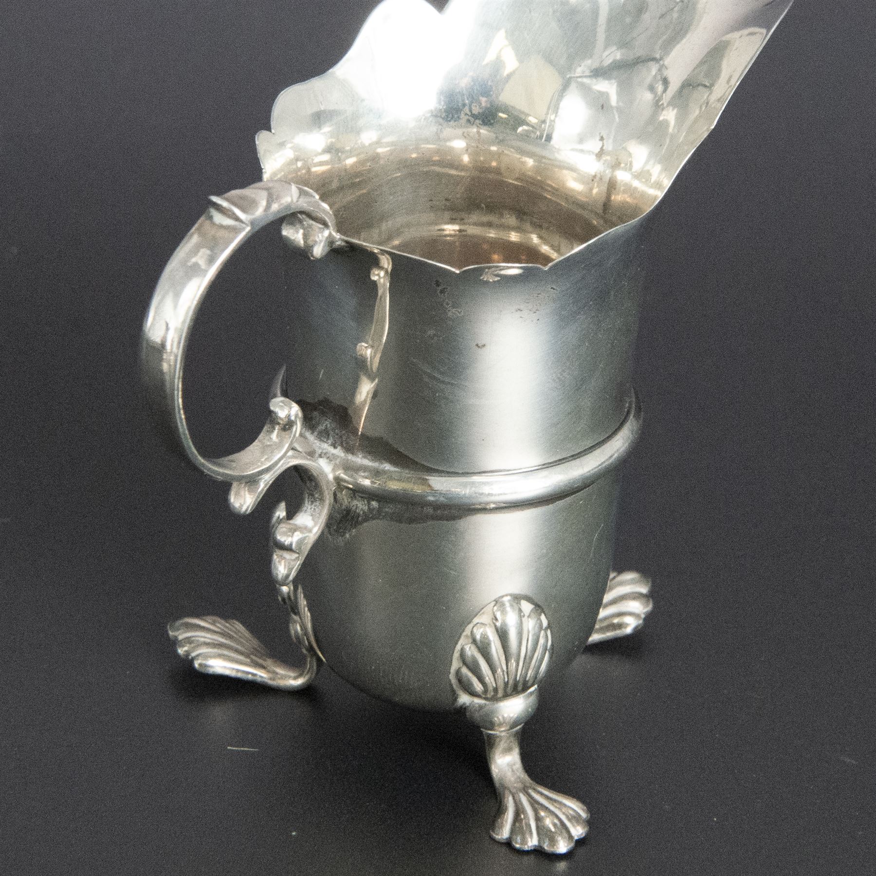 Group of early 20th century silver, comprising sauce boat, with flying scroll handle and upon three pad feet, two small cream jugs and a christening mug, all hallmarked, tallest H10cm