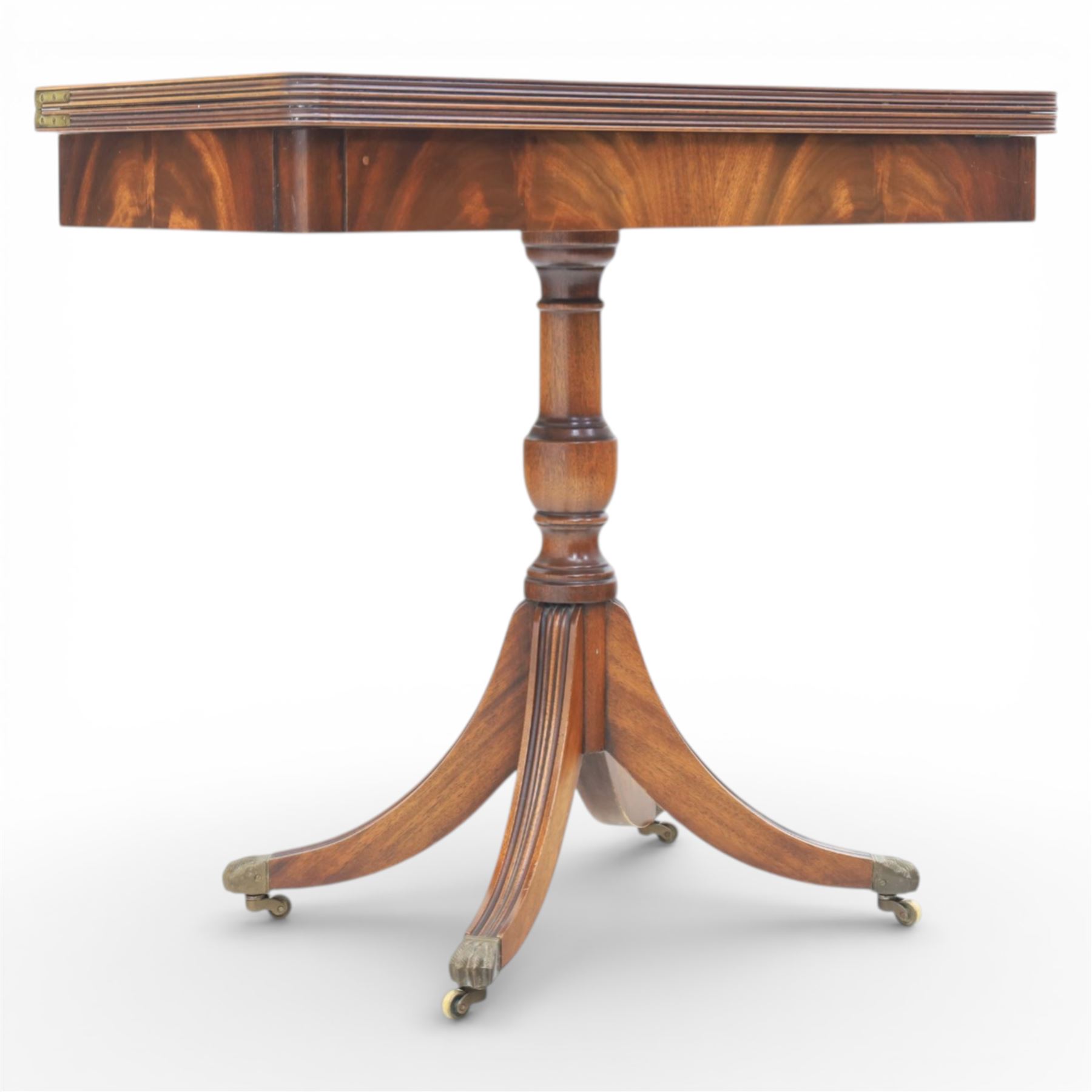 Victorian design mahogany card table, rectangular top with swivel and fold open action, revealing a baized lined interior, raised on turned baluster column, with reeded legs terminating in brass paw castors 