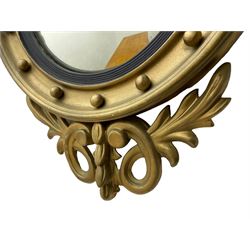 Pair of Regency period giltwood convex wall mirrors, moulded circular frame decorated with spherical mounts surmounted by a carved eagle with spread wings, foliage scroll carved upper and lower brackets, reed moulded and ebonised slip enclosed convex mirror plate 