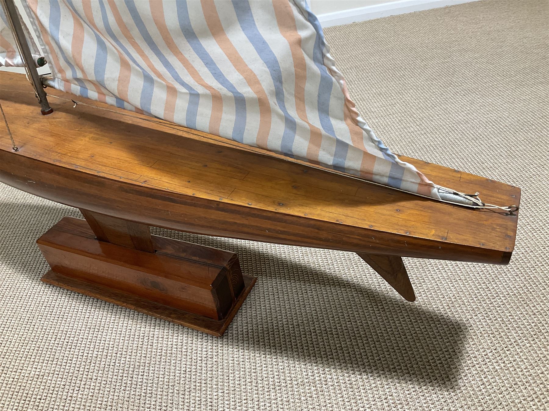 Large pond yacht with simulated planked mahogany deck, mahogany hull, wooden keel and stern fin and tubular aluminium mast with two sails; on wooden stand L131cm H on stand 177cm