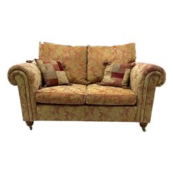 Duresta two seat sofa, upholstered in pale gold and rose fabric, mahogany feet; and matching rectangular footstool