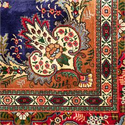 Persian Kashan rug, deep blue ground with central red and ivory lobed medallion framed by dense floral motifs, multiple borders with foliate and geometric design in red, blue and ivory, from the central Iran region