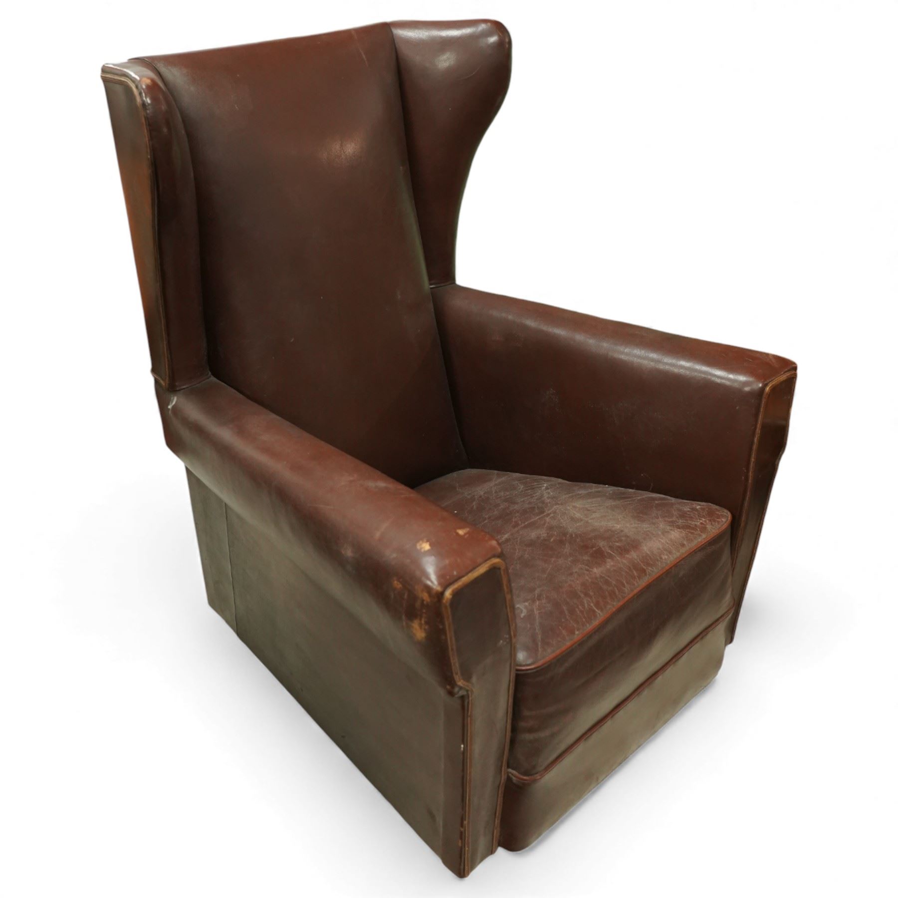 Early to mid 20th century pair of wingback armchairs, upholstered throughout in chocolate brown leather, the backs with deep wings, square padded arms with piped seams, loose seat cushions over solid bases