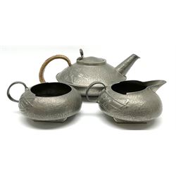 Archibald Knox for Liberty & Co Tudric pewter three piece tea service, comprising teapot with woven reed handle, single handled open sucrier, and milk jug, each with planished finish and detailed with honesty flowers, each impressed beneath Made in England Tudri Pewter 0231 