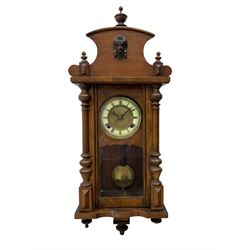Compact German striking wall clock in the Viennese style c 1910, in a mahogany case with applied carving and turned finials, with a fully glazed door, dial with an ivorine chapter and gilt centre, Roman numerals, minute track and gothic steel hands, 8-day spring driven movement with visible pendulum, wooden rod and spun brass bob. 