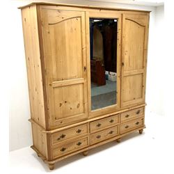 Solid pine wardrobe, moulded top above central mirrored panel flanked by two doors above six drawers, turned supports 