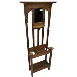 Edwardian oak hall stand, raised back with rectangular bevelled mirror plate surrounded by shelf and coat hooks, fitted with a glove box with hinged lid, over an undertier with two inset umbrella drip trays