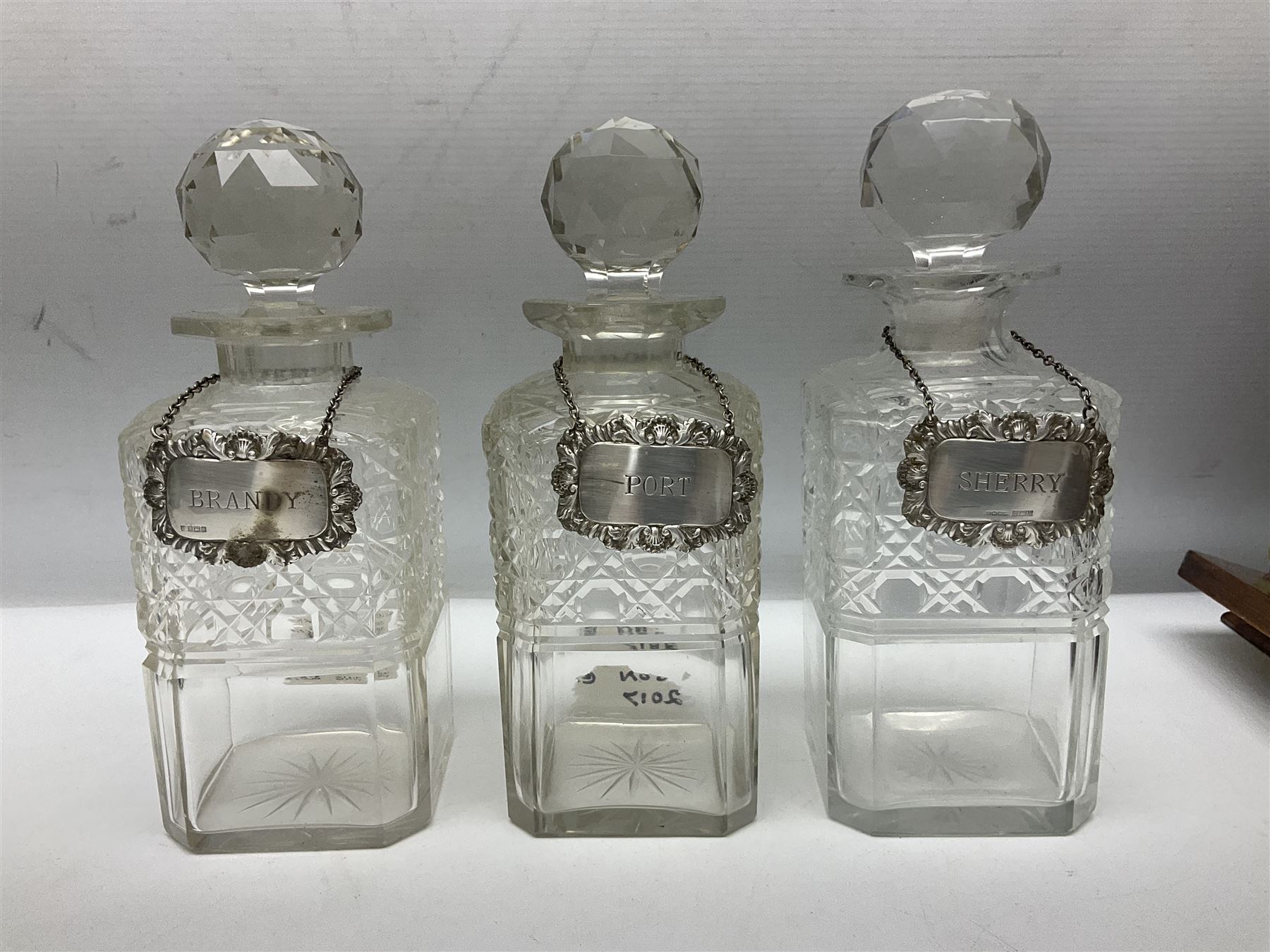 Edwardian oak three bottle tantalus, with brass mounts and three square sided cut glass decanters each with hallmarked silver decanter labels, complete with key, H31cm