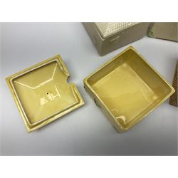 Four square honey boxes with lids,  each decorated with honeycomb pattern and finished with a bee finial