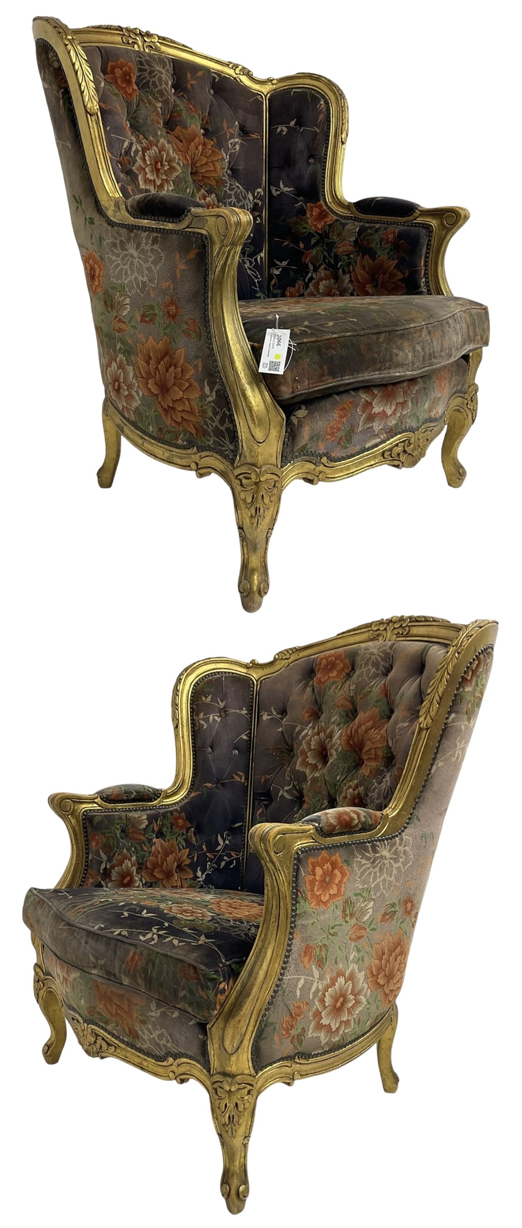 Pair of Louis XVI design gilt framed wingback armchairs, cresting rail carved and moulded with foliate decoration and C-scrolls, upholstered in buttoned floral patterned mauve velvet with loose seat cushion, scallop carved apron over cabriole supports