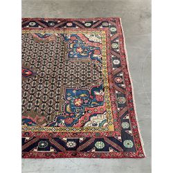 Persian Hamadan rug, the rosette pole medallion on a pale field decorated with stylised motifs, the blue band border decorated with stylised flower heads