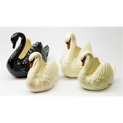 Four Dartmouth pottery jardinières or planters, modelled in the form of swans, comprising three white examples, and one black, marked beneath Dartmouth Devon England, larger examples H29cm, smaller examples H21.5cm. 